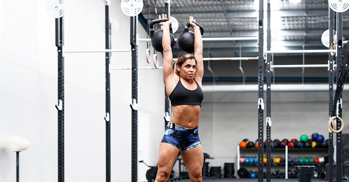 woman holding kettlebells overhead
