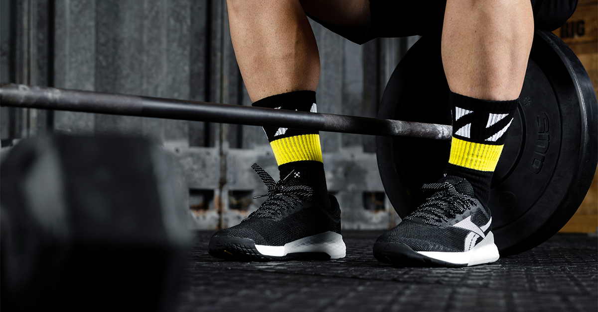 male athlete sitting next to barbell