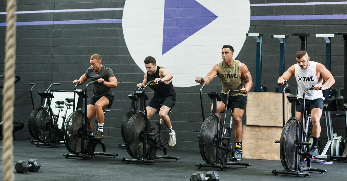 athletes riding air bikes