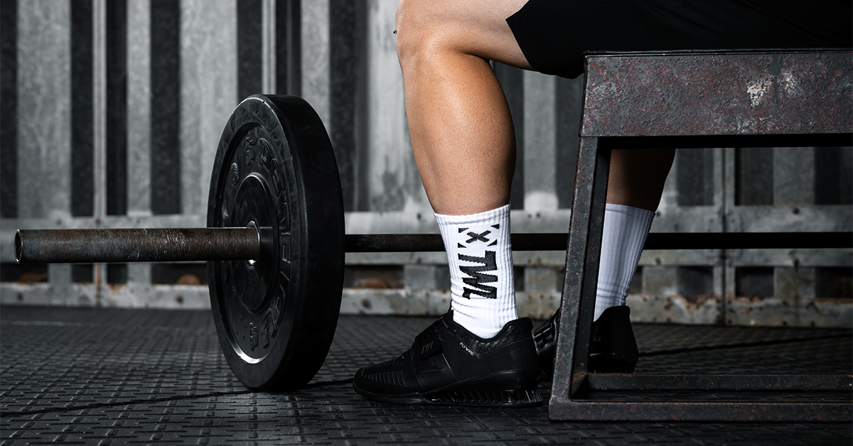 male athlete sitting next to barbell