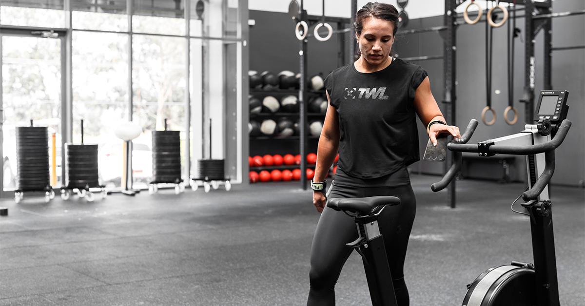 female athlete getting on stationary bike