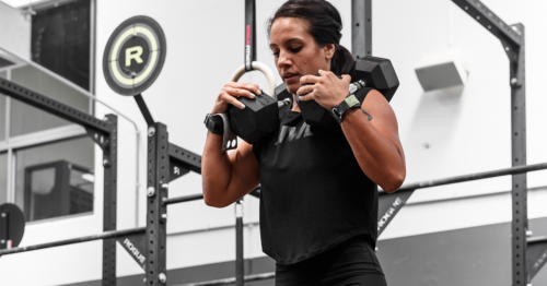 female athlete with dumbbells on shoulders