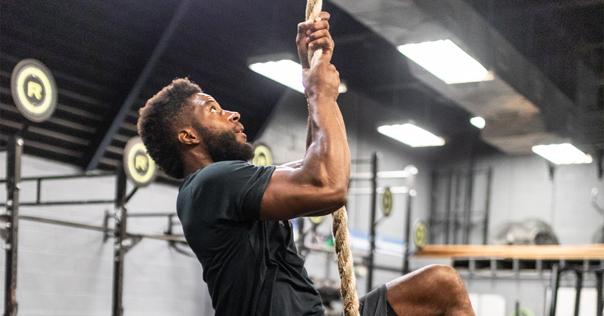 male athlete climbing rope