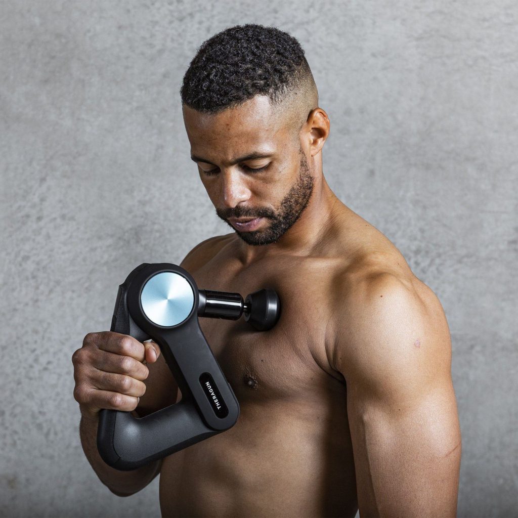male athlete using therabody theragun